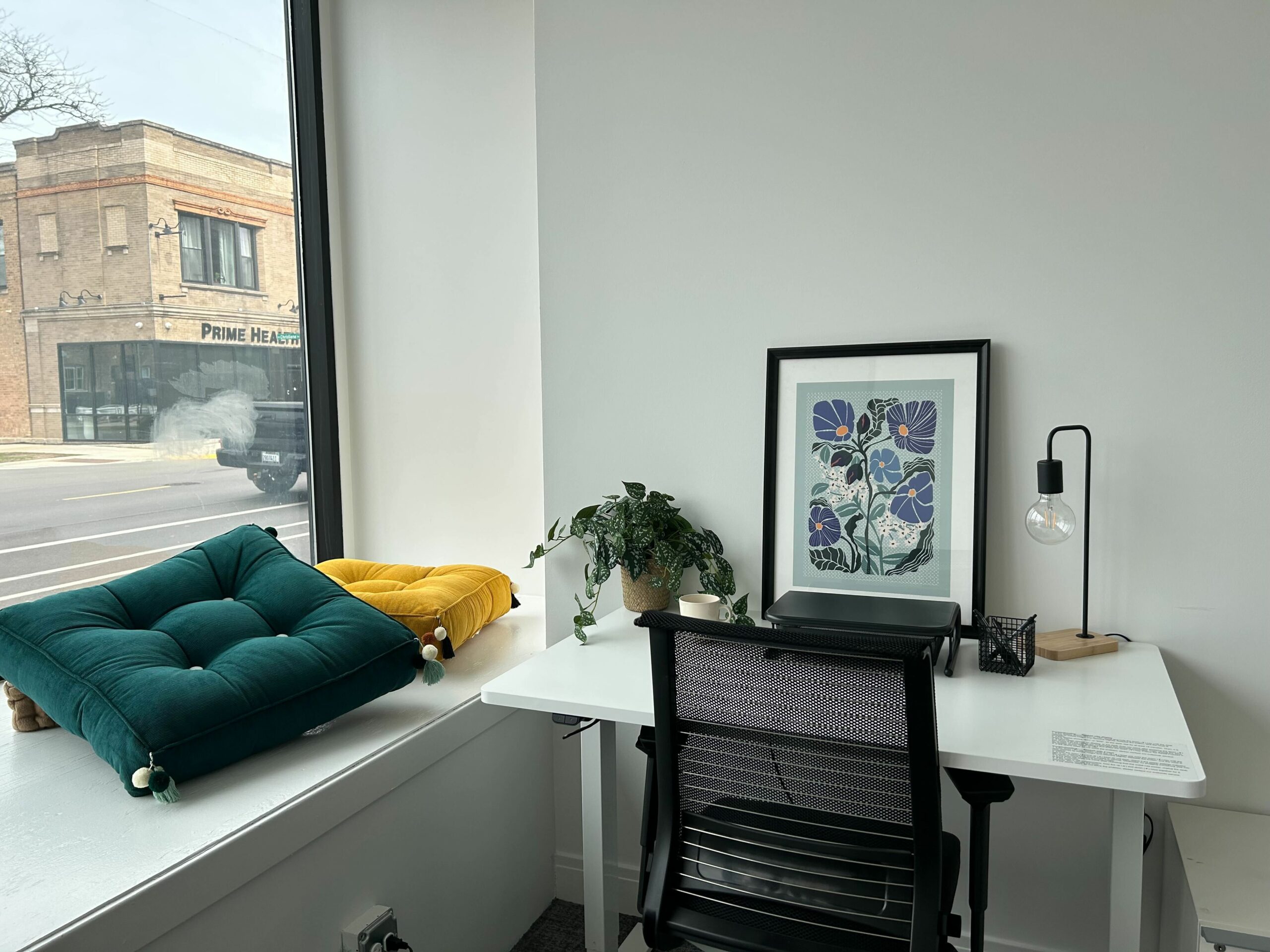 Windowed office with a standing table and yellow art in Chicago